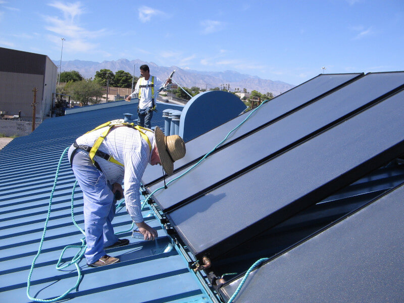 Solar technicians on roof installing solar water heating